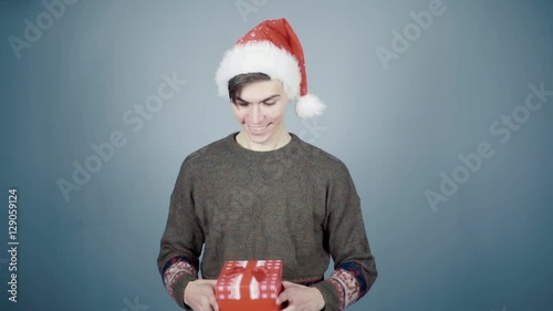 Man in Santa hat opening gift box unexpectedly hand from a box grabs him by nose photo