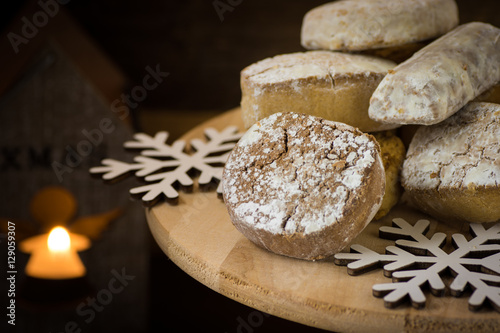 Traditional Spanish Christmas cookies polvorones, nevaditos and mantecados on a wood cake stand, lit candle, close up photo