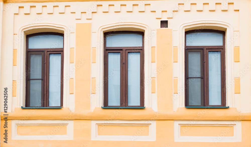 Three historic brown window on the yellow wall
