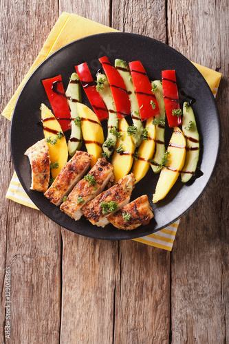 roast chicken with fresh mango, avocado and peppers with balsamic sauce close-up. vertical top view
