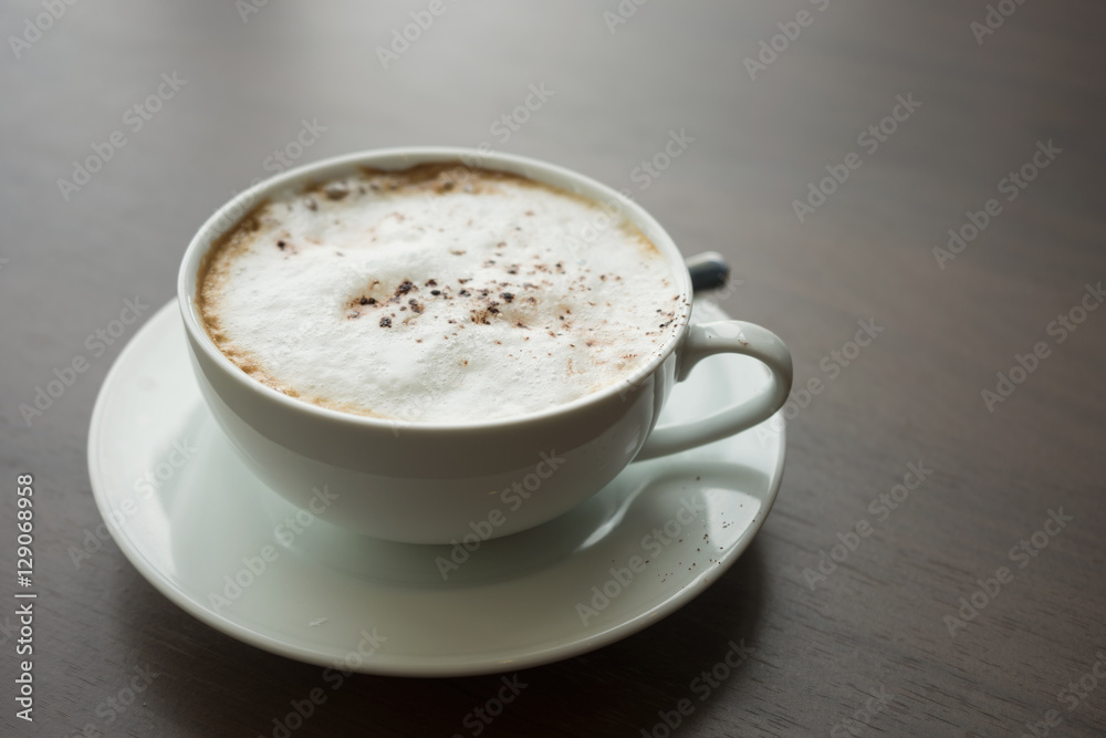 hot coffee in white cup white foam with silver spoon on wooden table at coffee time sunset / hot coffee hot coffee in white cup white foam with silver spoon on wooden table at coffee time sunset / hot coffee