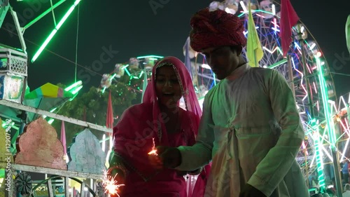 Indian couple in traditional dress with fire sparkle cracker at Diwali Mela festival in India  photo