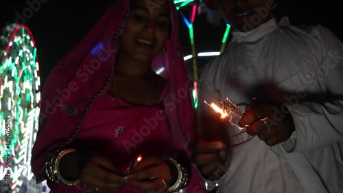 Indian couple in traditional dress with fire sparkle cracker at Diwali Mela festival in India  photo