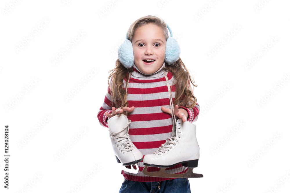 Lovely smiling little girl wearing colorful striped sweater and headdress, holding skates isolated on white background. Winter clothes. Lovely smiling little girl wearing colorful striped sweater and headdress, holding skates isolated on white background. Winter clothes.