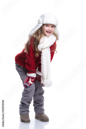 Cute smiling little girl with curly hairstyle wearing knitted sweater, scarf, hat and gloves isolated on white background. Winter clothes.