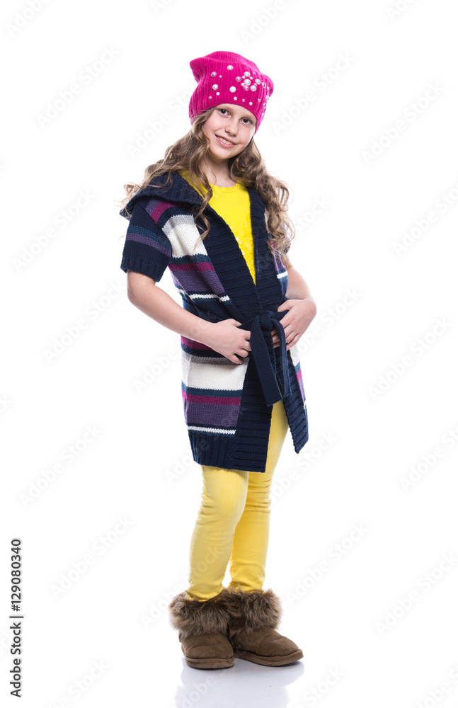 Cute smiling little girl with curly hairstyle wearing colorful sweater, shirt, pants and hat isolated on white background. Winter clothes. Cute smiling little girl with curly hairstyle wearing colorful sweater, shirt, pants and hat isolated on white background. Winter clothes.