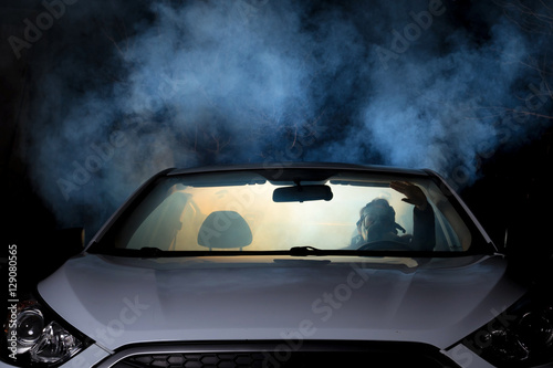 girl smoking cigarette in car full of smoke at night with gas mask © dinostock
