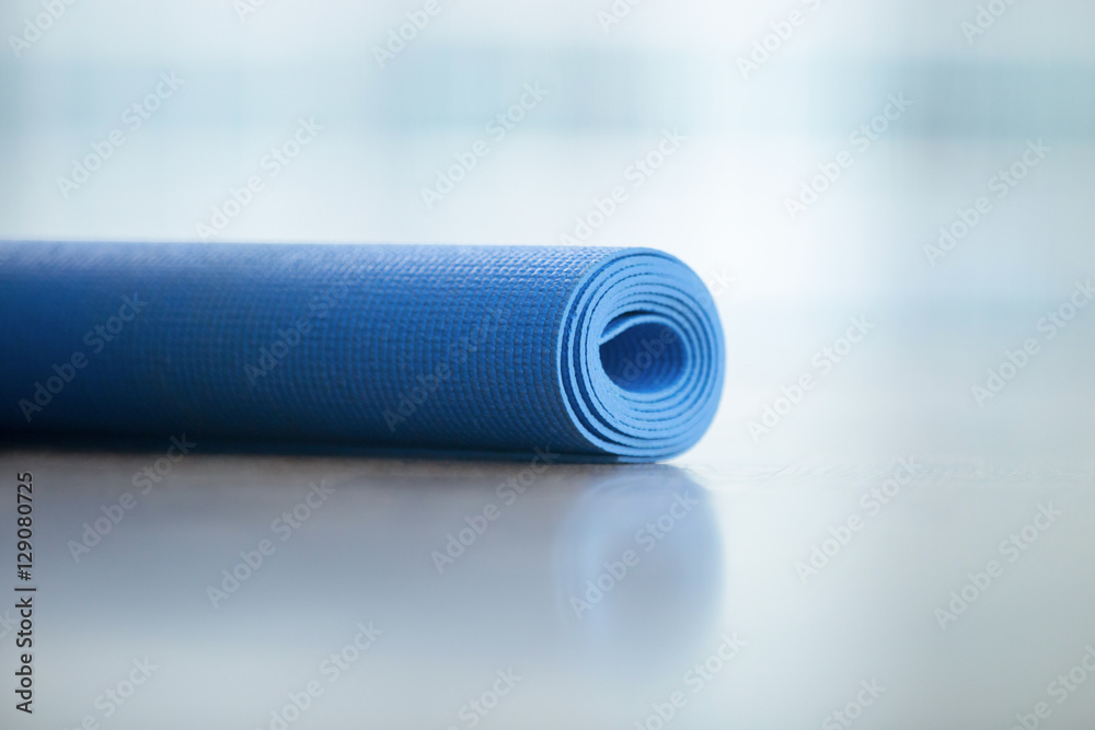 Close up of yoga, fitness floor mat in the yoga studio in a roll. Yoga props and accessories, aqua turquoise mat. Healthy lifestyle concept Close up of yoga, fitness floor mat in the yoga studio in a roll. Yoga props and accessories, aqua turquoise mat. Healthy lifestyle concept