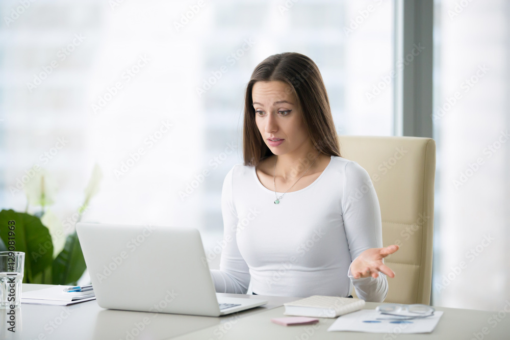 Young businesswoman at the modern office desk with laptop puzzled by a private photo posted, result of election, salary, world currency exchange rates, can not believe her eyes Young businesswoman at the modern office desk with laptop puzzled by a private photo posted, result of election, salary, world currency exchange rates, can not believe her eyes