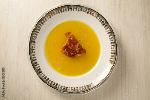 Pumpkin Soup with proschiuto on table photo