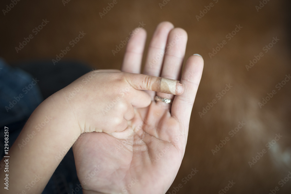 子供の指先に絆創膏を貼る母の手 子供の指先に絆創膏を貼る母の手
