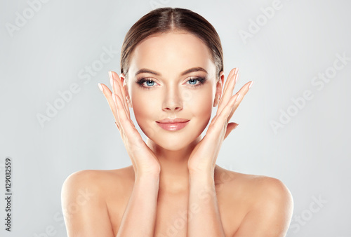 Beautiful Young Woman with Clean Fresh Skin touch own face . Facial treatment . Cosmetology , beauty and spa 
