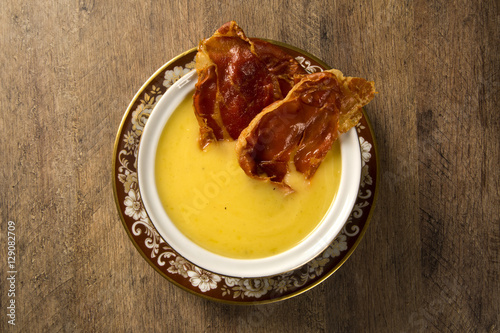 Pumpkin Soup with proschiuto on table photo