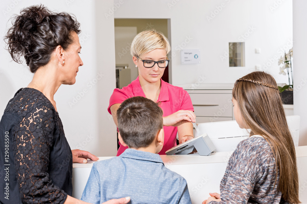 Mutter mit Kindern beobachtet Zahnarzthelferin beim einlesen der Mutter mit Kindern beobachtet Zahnarzthelferin beim einlesen der
