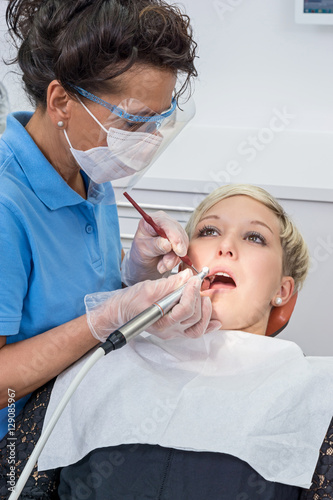 Zahnarzthelferin bei Zahnreinigung an Patientin