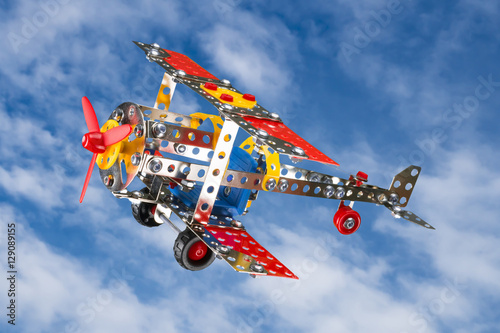 Toy plane built with small pieces of metal and plastic, shot on sky background photo