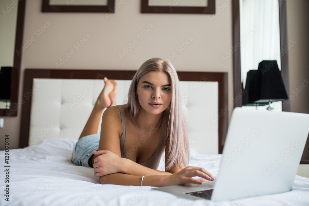 Beautiful young girl in black underwear with laptop in bed at home