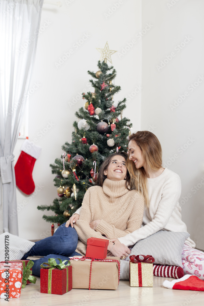 Young beautiful women next to Christmas tree with Christmas presents, Christmas morning Young beautiful women next to Christmas tree with Christmas presents, Christmas morning