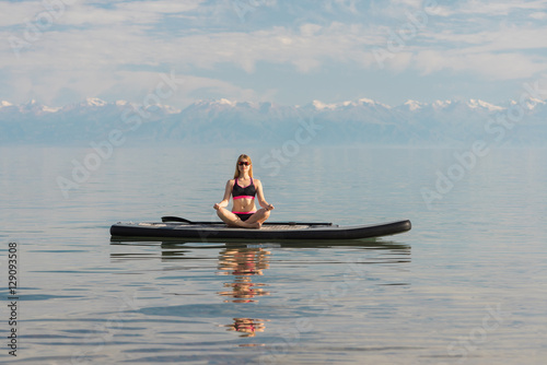 Photography woman on paddle board doing yoga mountains background