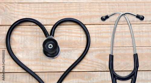 Medical stethoscope in a heart shape on wood table background