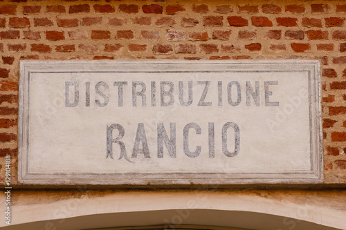 Fototapeta Naklejka Na Ścianę i Meble -    old sign ration-distribution written in  italian language / sign made of cement indicating the writing ration-distribution  on a bricks wall