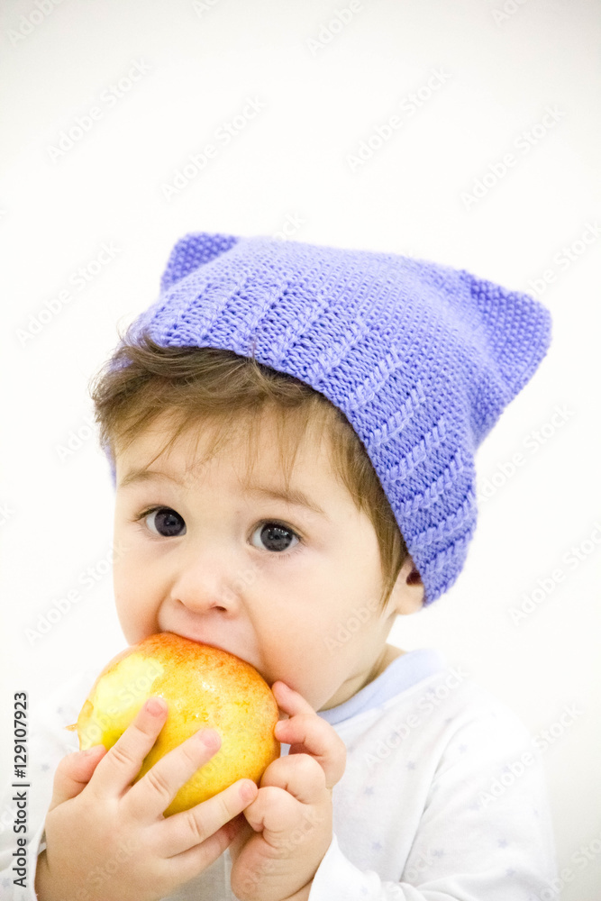 Cute little caucasian boy 11 months old sits and eats red apple on white background Cute little caucasian boy 11 months old sits and eats red apple on white background
