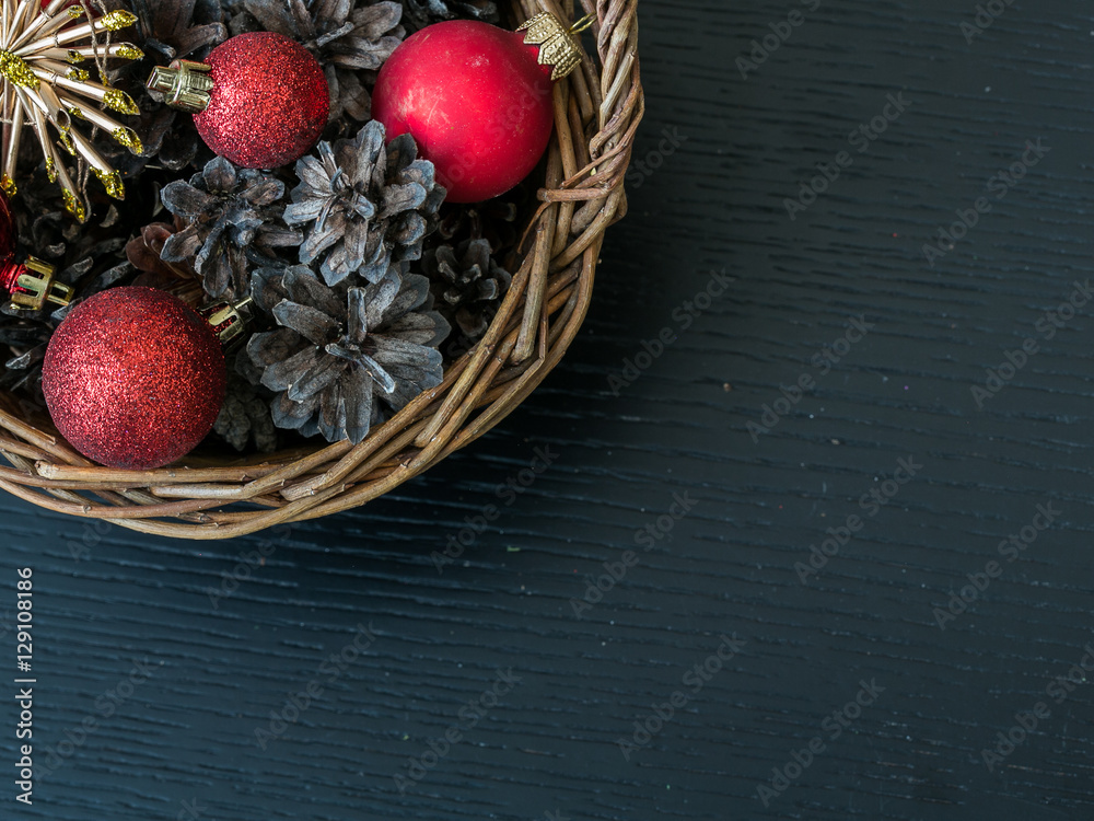 New year and Christmas decorations. A holiday basket with pine cones, red garnet and nuts on a snow like carpet, new year tree with toys on the background, copy space. Christmas Box Basket Pine Cone. New year and Christmas decorations. A holiday basket with pine cones, red garnet and nuts on a snow like carpet, new year tree with toys on the background, copy space. Christmas Box Basket Pine Cone.