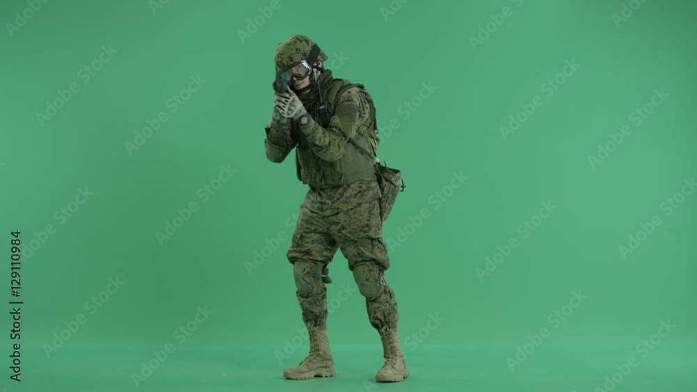 Soldier standing and targeting at camera at green screen