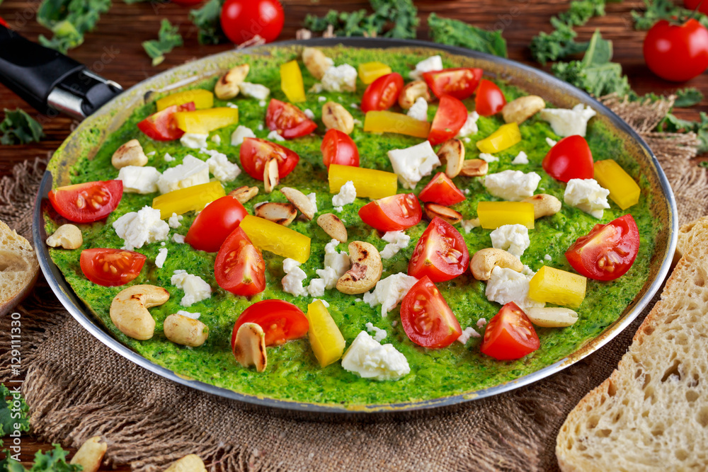Vegetable Green Omelette with tomatoes, kale, greek cheese, olives, nuts, toast on wooden background. concept healthy food