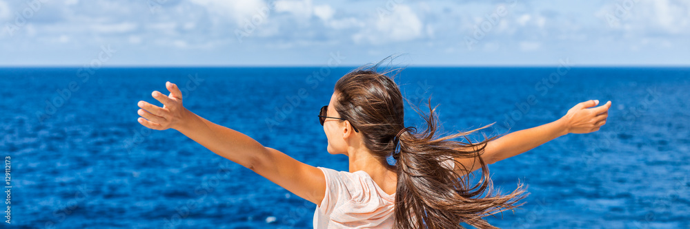 Happy freedom woman with open arms looking at blue sea horizon outdoors. Carefree person living a free life. Panorama horizontal banner crop for success and bliss concept. - obrazy, fototapety, plakaty 