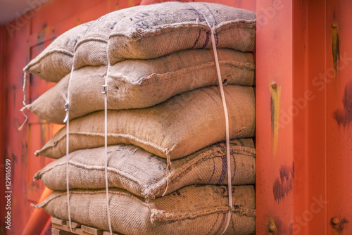 Foto Jute sacks stacked in a warehouse - Cropped image with a pile of burlap bags full of goods, stacked on a pallet in a storage and ready for shipment