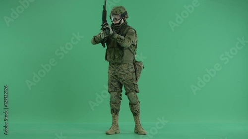 Soldier standing and targeting around at green screen photo