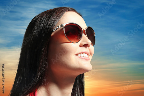 Young woman in sunglasses on sky background © Africa Studio