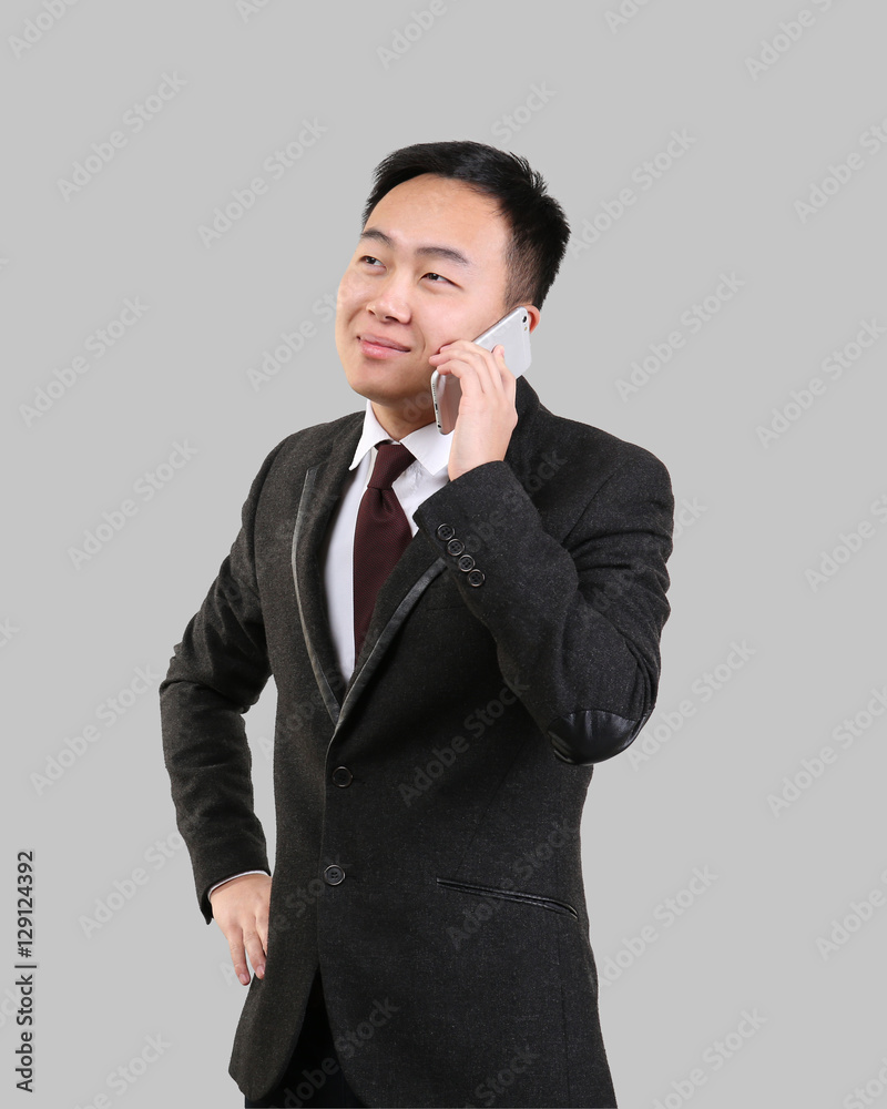 Handsome Asian man talking by mobile phone, on light background Handsome Asian man talking by mobile phone, on light background