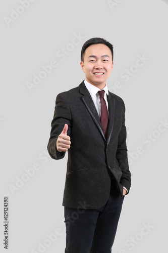 Handsome Asian man showing thumb up sign, on light background