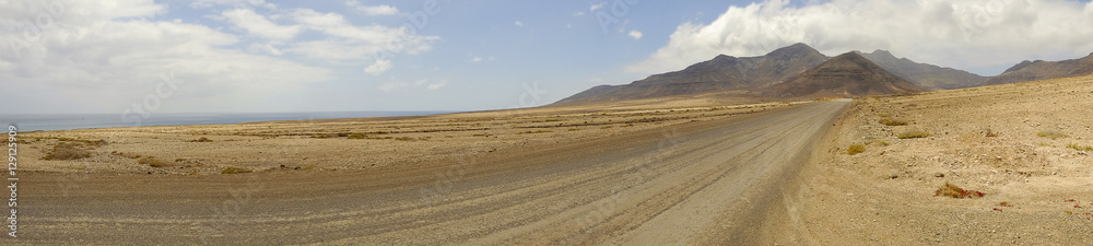 View on the road, the mountains and blue ocean on Fuerteventura, Spain. View on the road, the mountains and blue ocean on Fuerteventura, Spain.