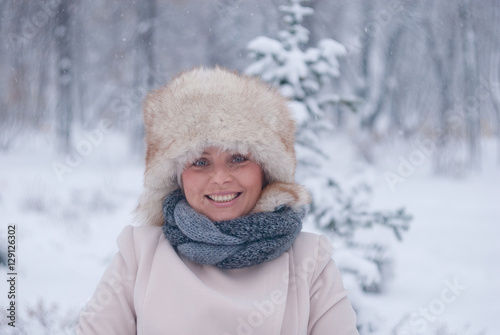 Winter portrait of a woman in white coat during snowfall in a park