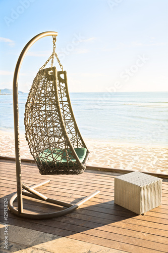 Cozy hanging resting chair on decking by sea side at evening sun © 18042011