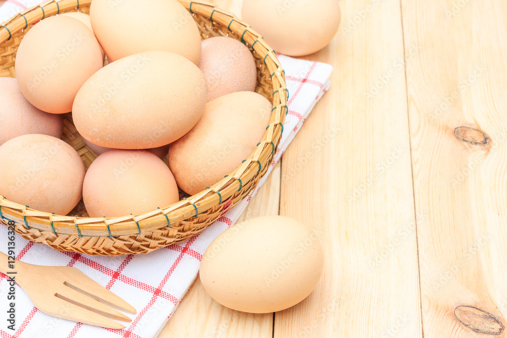 Fresh egg in the basket weaving over wooden table background, Top view with copy space and text.