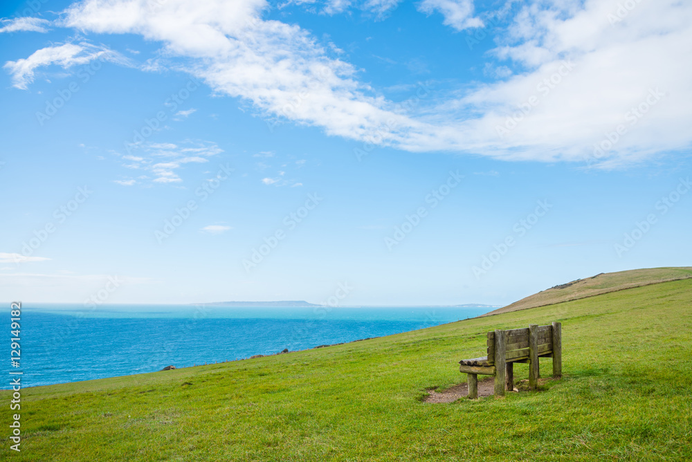 Old wooden chair on hill with sky and ocean background