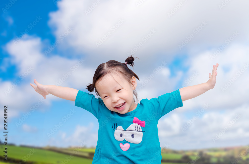 Happy little Asian girl on the field with sky background Happy little Asian girl on the field with sky background
