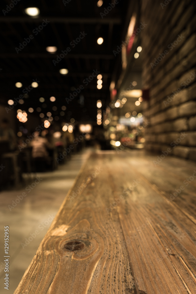Empty wood table top of bar with blur of cafe restaurant in dark