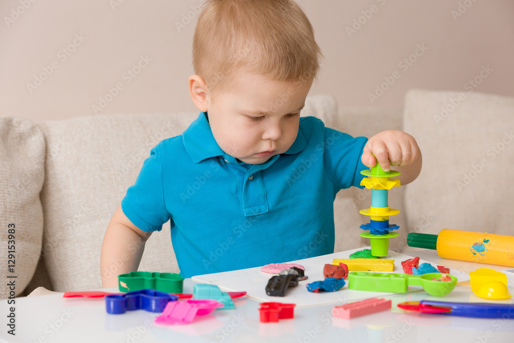 Child with colorful clay. Toddler playing and creating toys from play dough. Boy molding modeling clay. Child with colorful clay. Toddler playing and creating toys from play dough. Boy molding modeling clay.