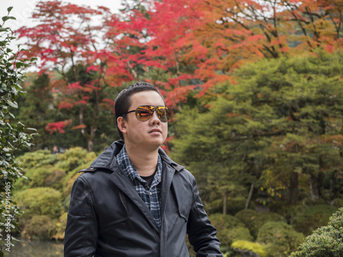 a man relaxing with a beautiful Japan , Nikko autumn tree . focus on the model . Japan autumn set