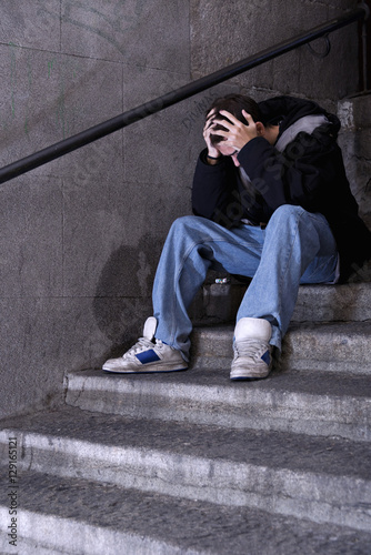 Depressed young man sitting on a public stairs