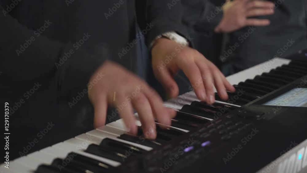 close up details on try out pop or rock band indoors. Man hands playing on synth electronic musical instrument.