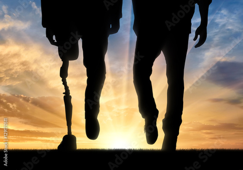 Leg with artificial limb and normal feet on sunset photo