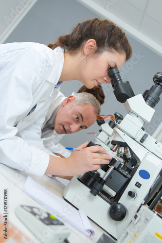 male and female scientists using microscopes in laboratory