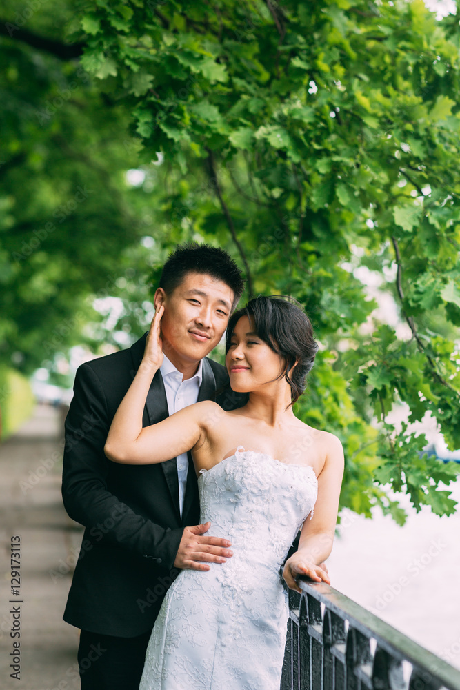 Chinese Wedding couple standing in the alley of green leaves