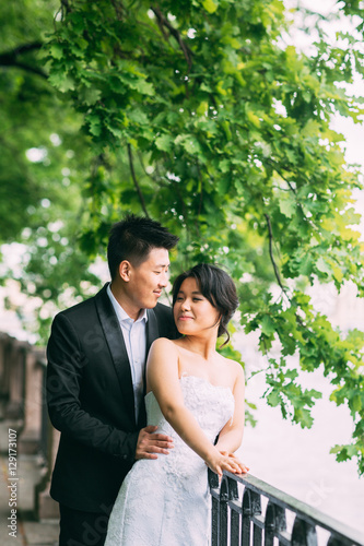 Chinese Wedding couple standing in the alley of green leaves © cmirnovalexander